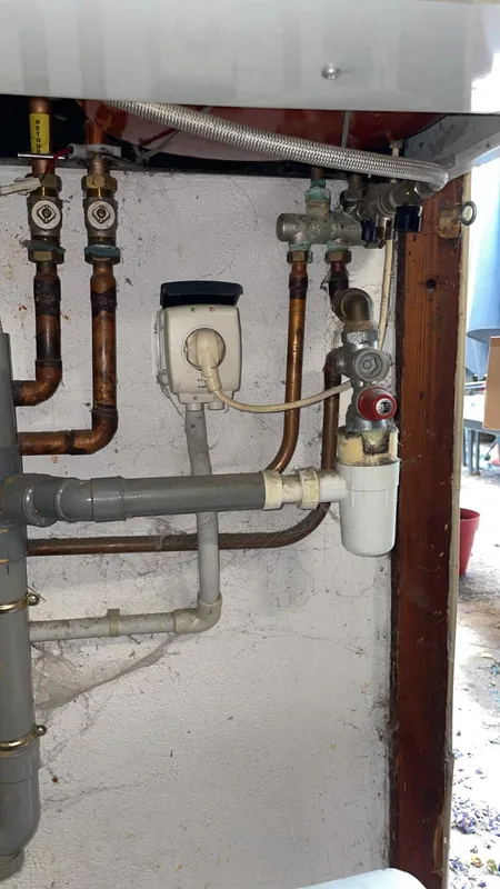 Raccordements cuivre et siphon sous un chauffe-eau mural